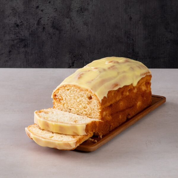 Sliced lemon drizzle loaf cake with yellow icing glaze