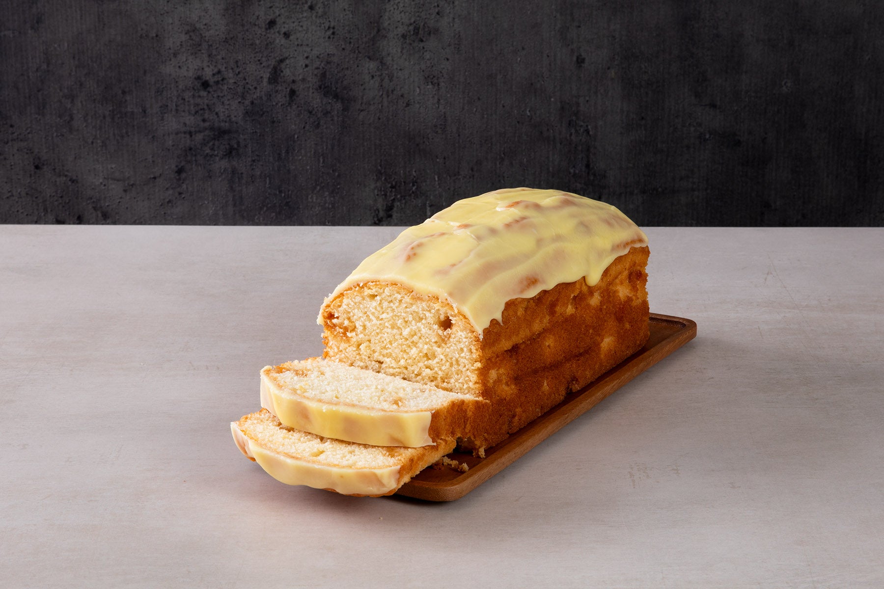 Sliced lemon drizzle loaf cake with yellow icing glaze