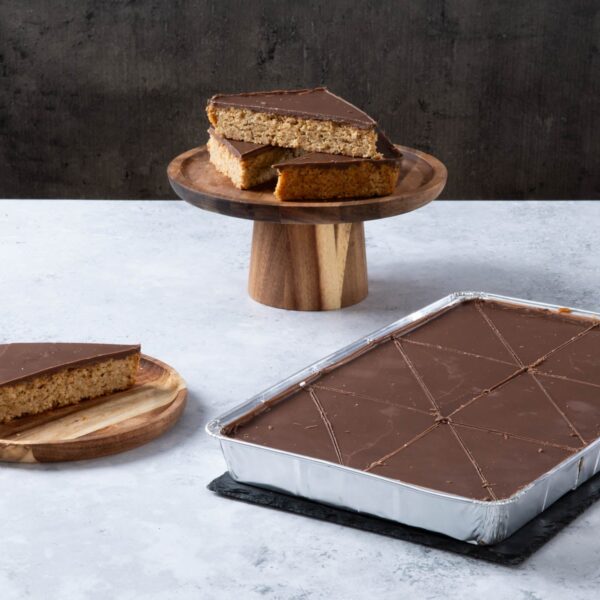 Chocolate-topped oat traybake slices on wooden plates.