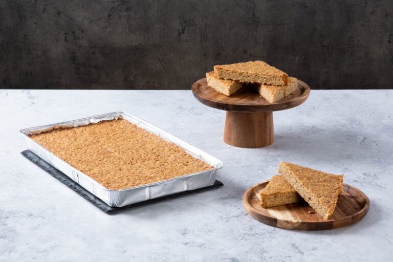 a golden traybake with sliced pieces on wooden plates