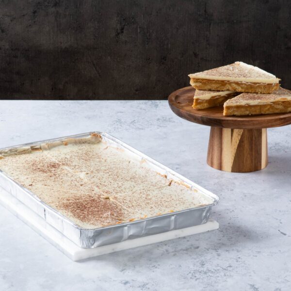 Caramel shortbread slices with a creamy topping on a wooden stand.