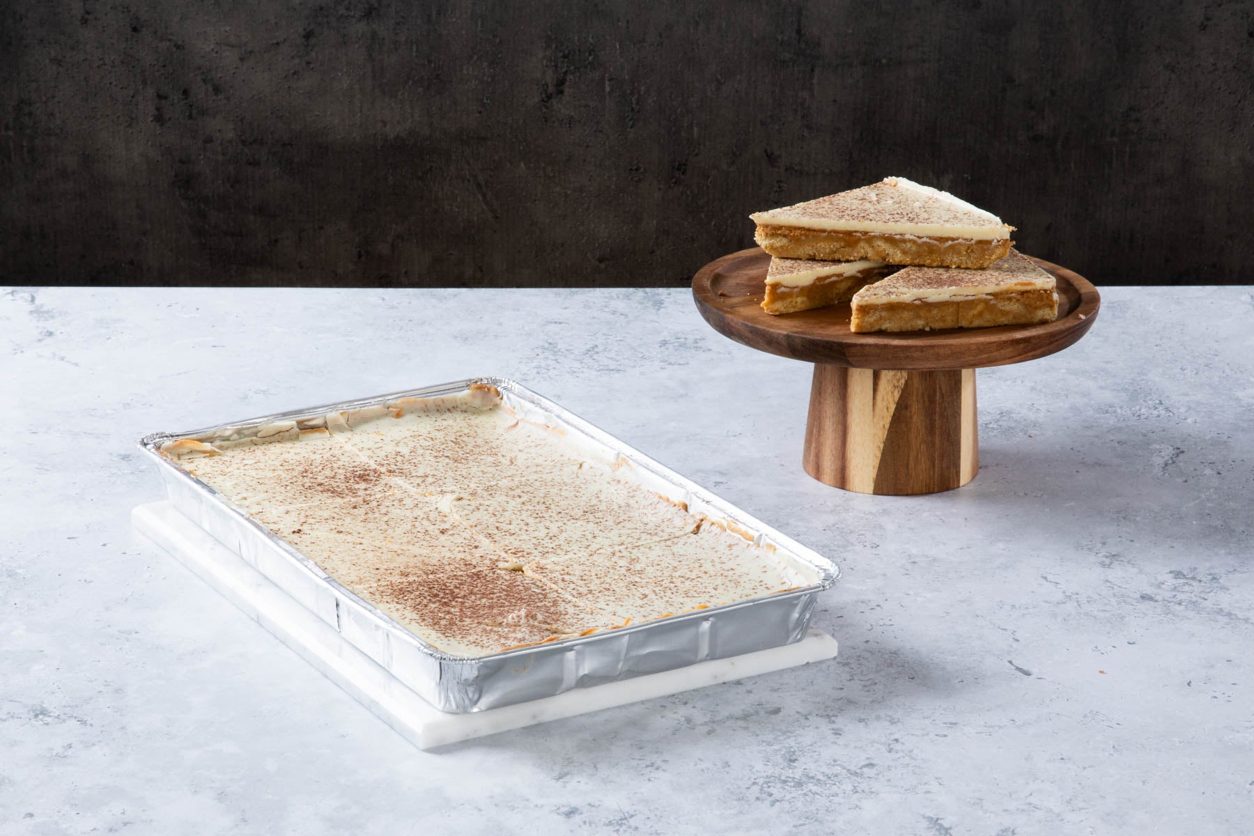 Caramel shortbread slices with a creamy topping on a wooden stand.