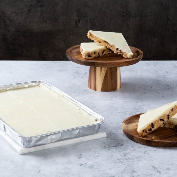 Chocolate cake with creamy frosting and chocolate topping on a wooden board.