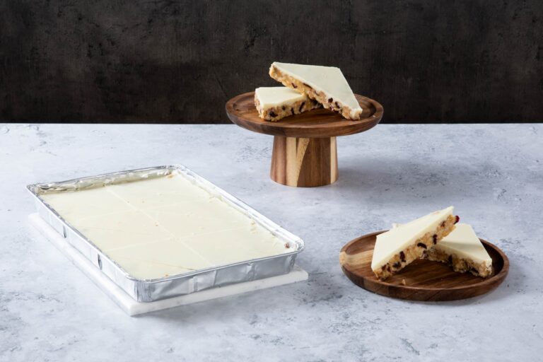 Chocolate cake with creamy frosting and chocolate topping on a wooden board.