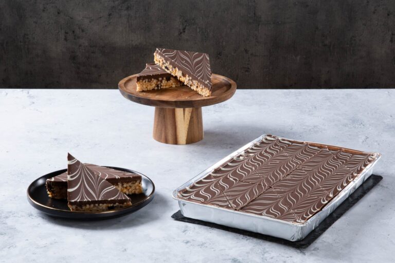 Chocolate crispy cake slices with marbled chocolate topping on a wooden stand.