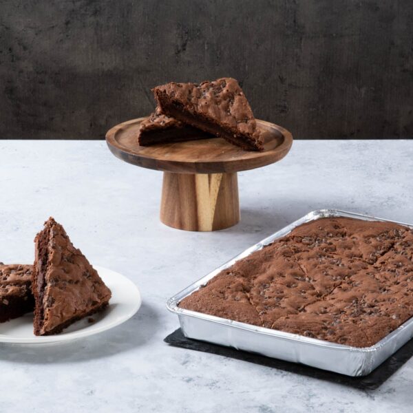 Chocolate brownie traybake with chocolate chips, served sliced and in a baking tray.