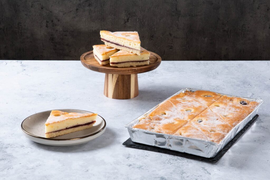 a square sponge traybake with a dark berry filling