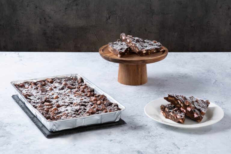 Chocolate rocky road traybake with sliced pieces and icing sugar.