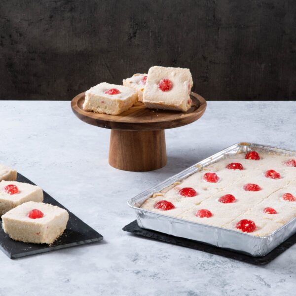 Raspberry coconut traybake slices on a wooden cake stand.