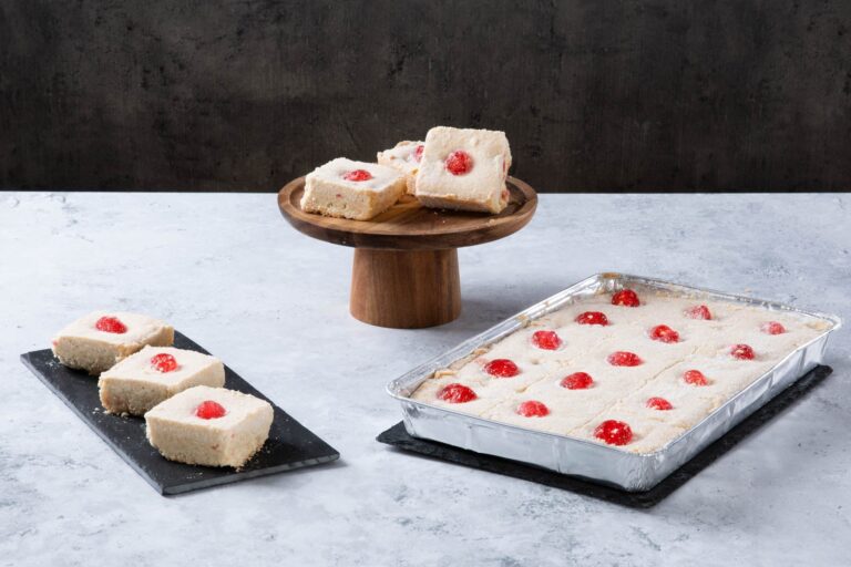 Raspberry coconut traybake slices on a wooden cake stand.
