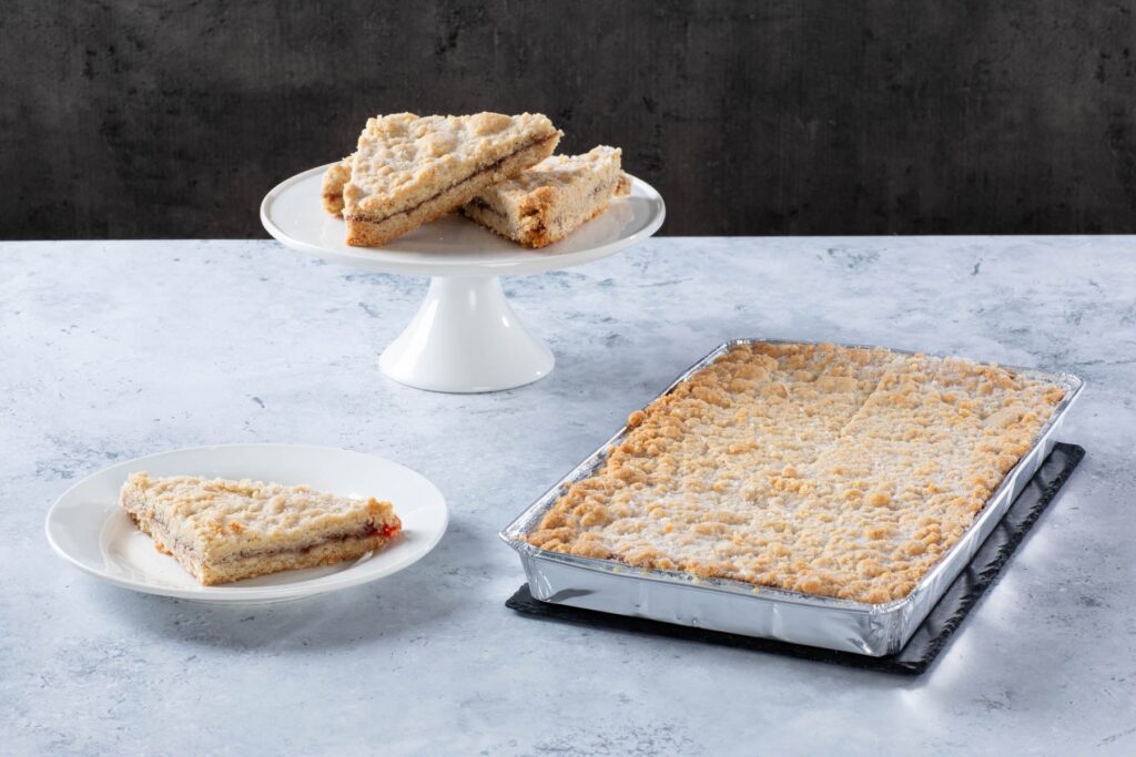 a crumb-topped traybake with sliced pieces on plates