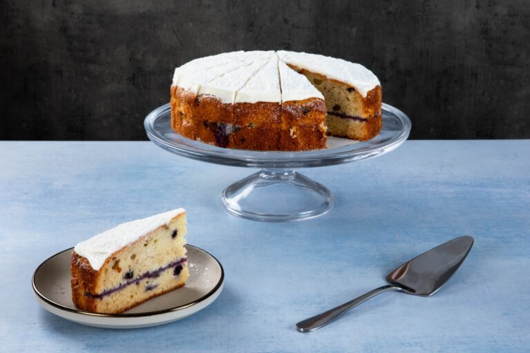 a blueberry cake with white frosting and a slice on a plate