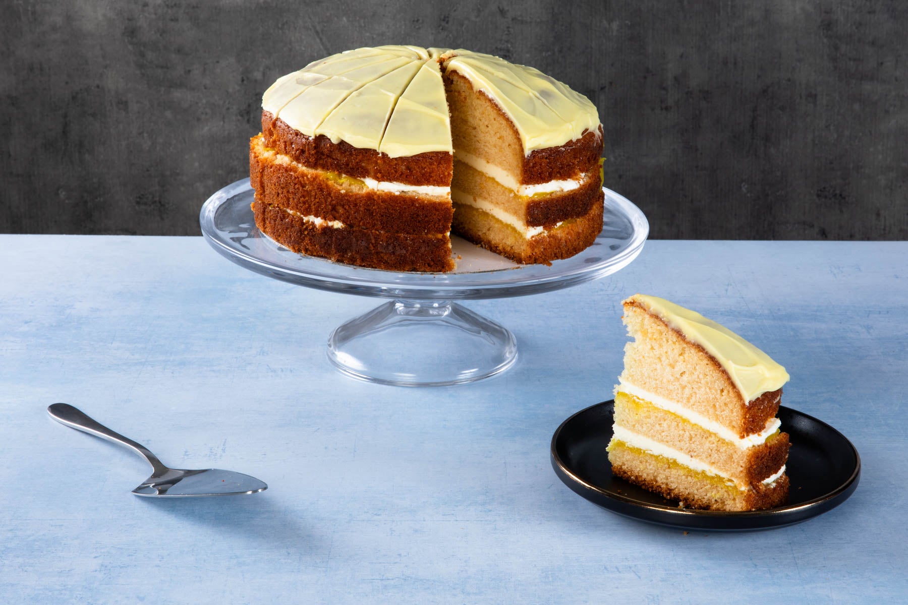 Lemon drizzle cake slices with lemon icing on a wooden board.