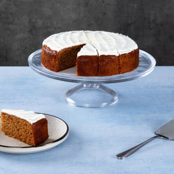 Chocolate cake with creamy frosting and chocolate topping on a wooden board.