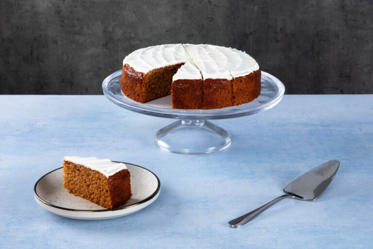 Chocolate cake with creamy frosting and chocolate topping on a wooden board.