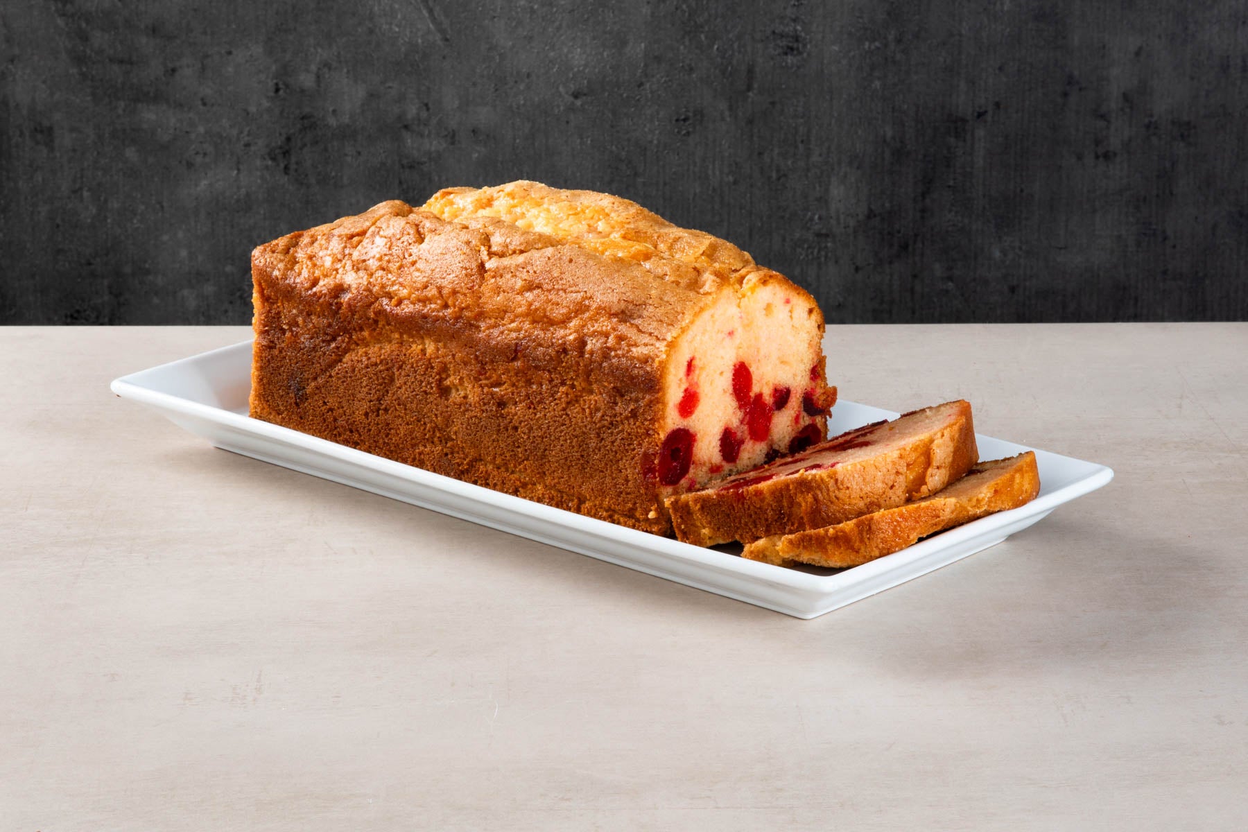 Cherry loaf cake with sliced pieces on a white plate.
