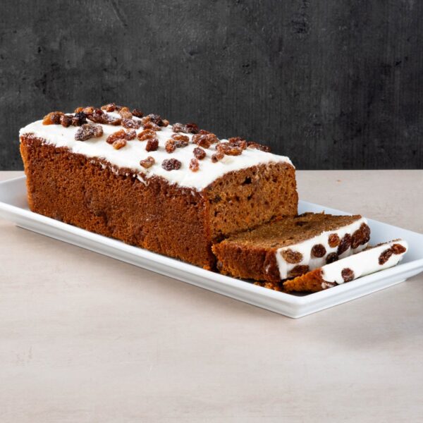 Carrot and raisin loaf cake with white icing and sliced pieces.