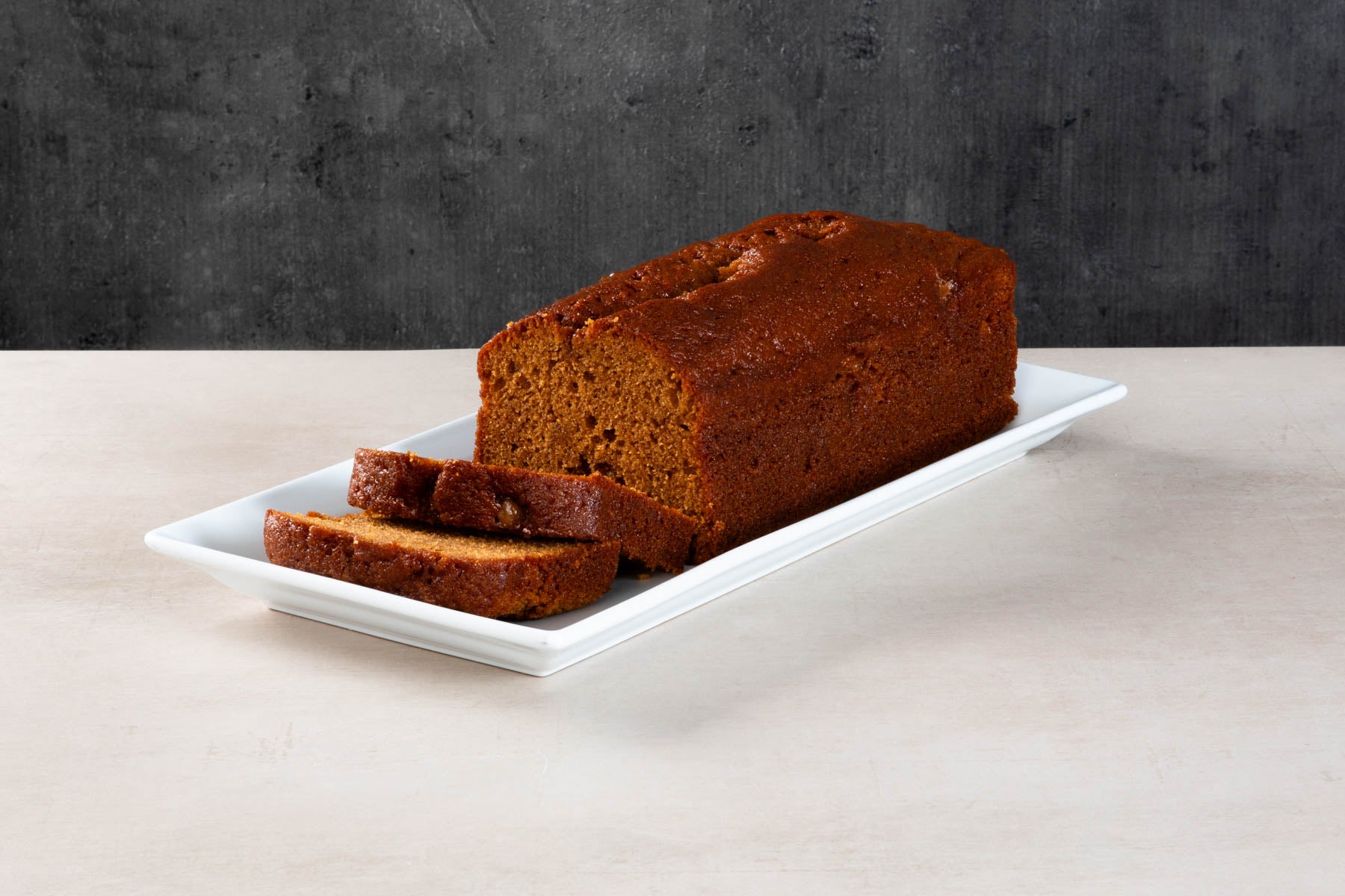 Sliced sticky toffee loaf cake on a white platter