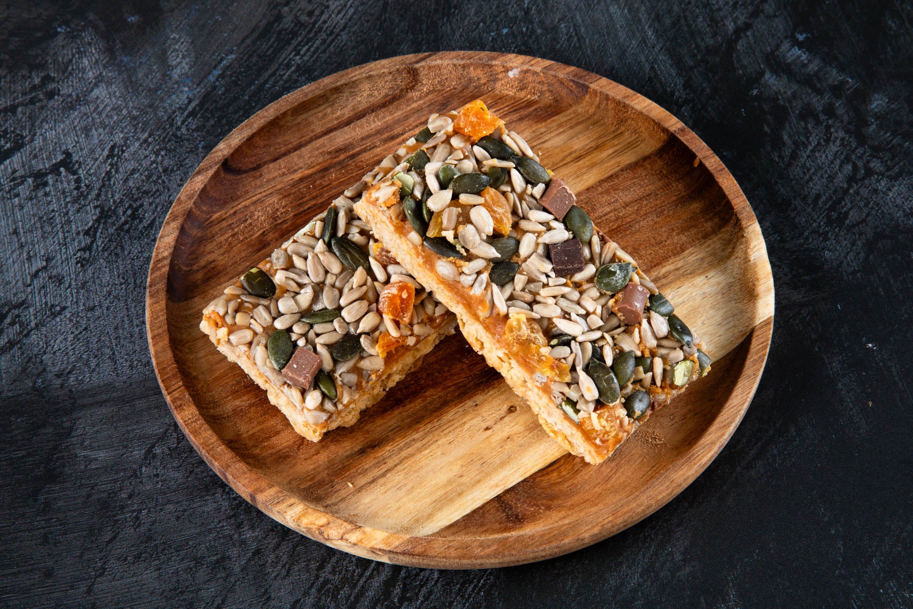 Apricot and seed flapjack slices on a wooden plate.